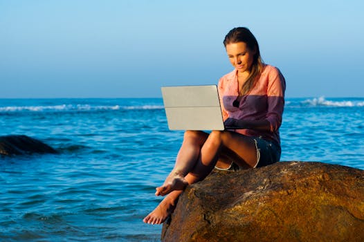 a digital nomad working on a laptop at a beach